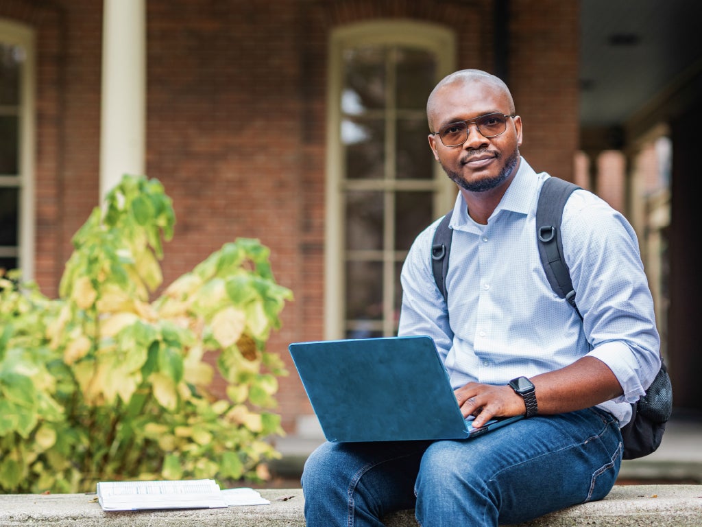 Student Success Student using a laptop outside a campus building